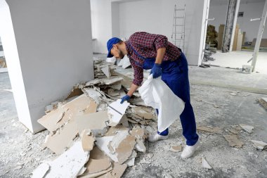 Construction worker with used building materials in room prepared for renovation