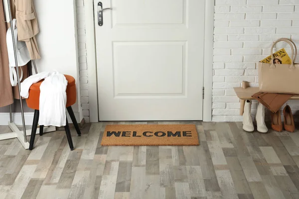 Doormat with word Welcome on wooden floor in hall