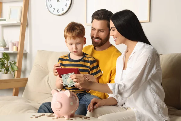 家庭で貯金箱にお金を入れて計算機で幸せな家族 — ストック写真