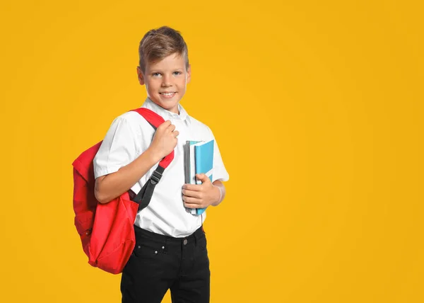 黄色の背景にバックパックとノートブックを持つ小さな男の子 学校に戻る — ストック写真