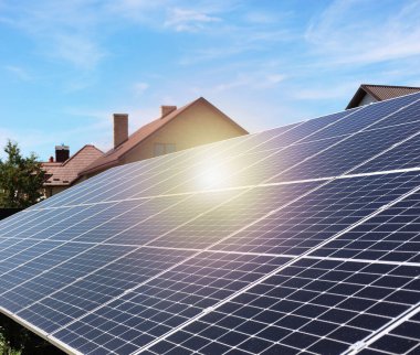 Güneşli bir günde mavi gökyüzünün altındaki evlerin yakınındaki güneş panelleri. Alternatif enerji kaynağı