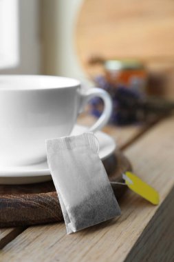 Tea bag and cup on wooden table indoors, closeup