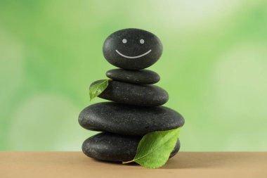 Mutlu yüzü çizilmiş taş yığını ve bulanık arka planda yeşil yapraklar. Zen kavramı