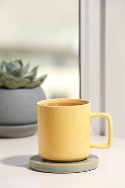 Sarı çay fincanı ve ahşap pencere eşiğinde sulu