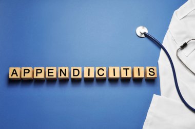 Tahta küplerden yapılmış kelime apandisiti ve mavi arka planda steteskop olan doktor üniforması. Metin için boşluk