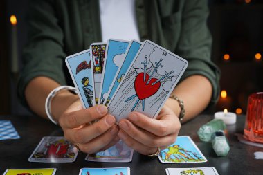 İçerideki gri masada tarot kartlarıyla falcı, yakın plan.