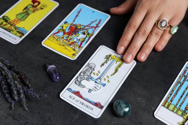 Falcı, gri masada tarot kartlarının yayılması üzerine geleceği tahmin ediyor, yakın plan.