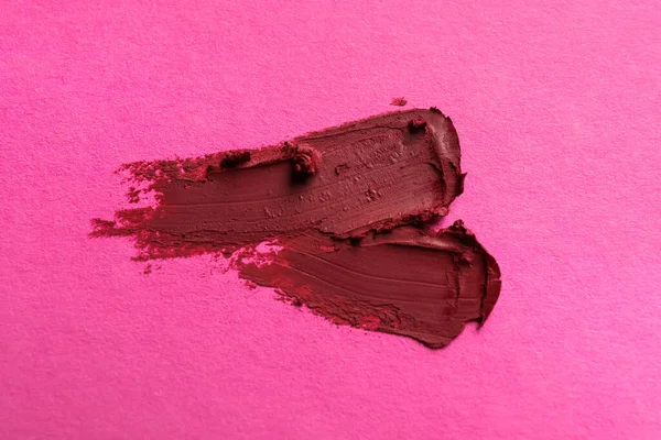 Smears of beautiful lipstick on pink background, top view