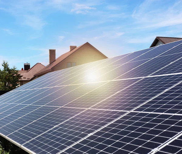 Solar panels near houses under blue sky on sunny day. Alternative energy source