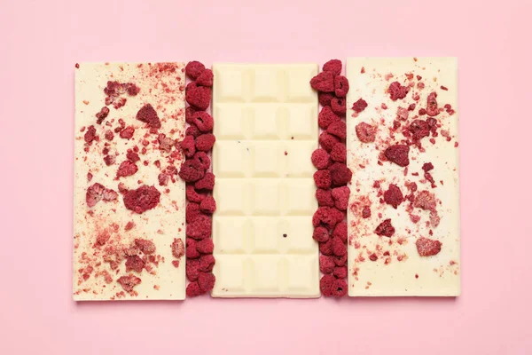 White chocolate bars with freeze dried fruits on pink background, flat lay