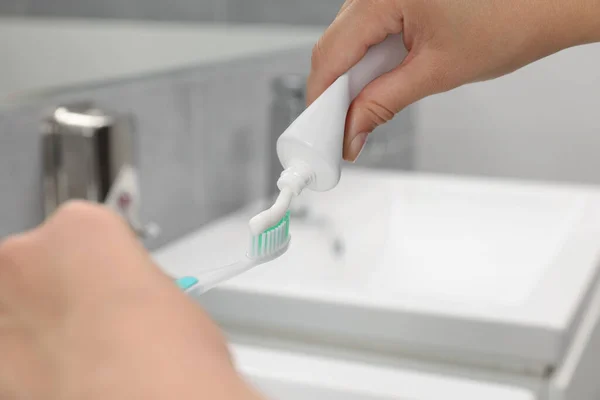 バスルームのブラシに歯磨き粉を適用する女性 クローズアップ — ストック写真