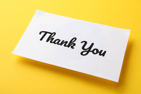 Белая бумажная записка с фразой Спасибо на желтом фоне