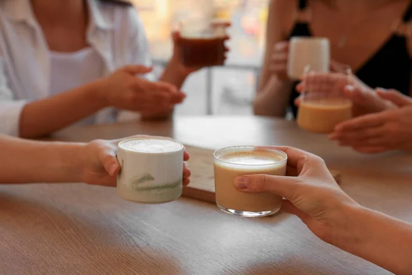 Stock image Friends drinking coffee at wooden table in cafe, closeup