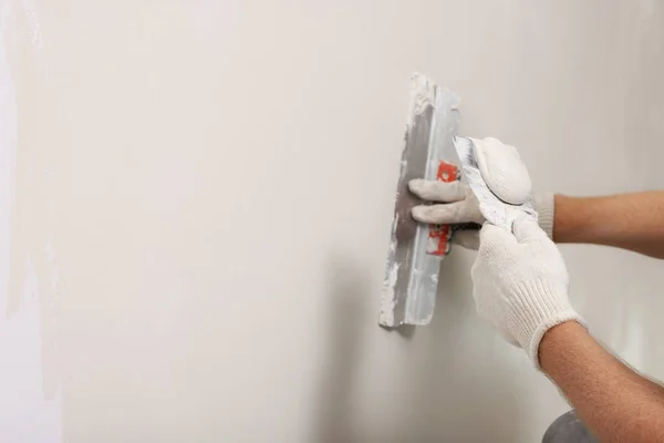 stock image Worker plastering wall with putty knife indoors, closeup. Space for text