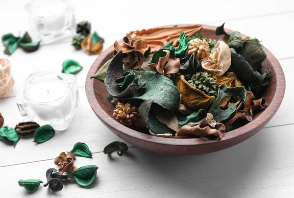 Aromatic potpourri of dried flowers in bowl on white wooden table