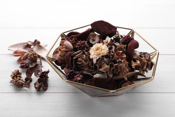 Aromatic potpourri of dried flowers in bowl on white wooden table