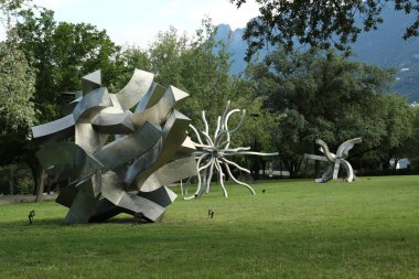 Yeşil çimlerin üzerinde metal figürler olan güzel park manzarası