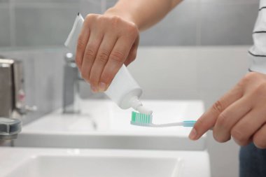 Banyoda diş fırçasına diş macunu süren kadın, yakın plan.