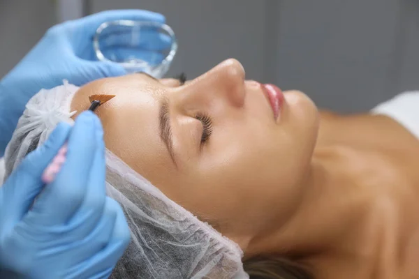 美容师在美容院病人脸上应用化学剥皮产品 — 图库照片