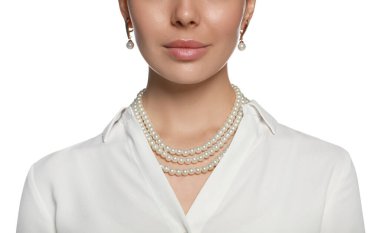 Beyaz arka planda zarif inci takılar takan genç bir kadın, yakın plan.