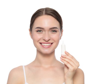 Young woman holding tube of eye cream on white background