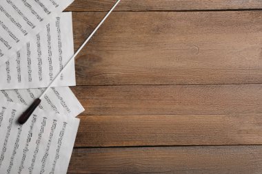 Orkestra şefinin copu ve notaları ahşap masada, düz yerde. Metin için boşluk