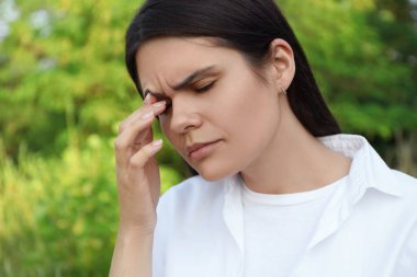 Young woman suffering from eyestrain outdoors on sunny day