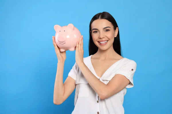 Jovem Feliz Com Banco Porquinho Fundo Azul Claro — Fotografia de Stock