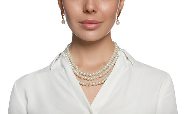 Молодая женщина носит элегантные жемчужные украшения на белом фоне, крупным планом