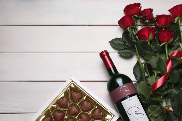 一壶红葡萄酒 美丽的玫瑰和心形巧克力糖果放在白色的木制桌子上 平平的躺着 案文的篇幅 — 图库照片