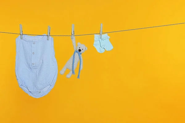 オレンジを背景に洗濯物を乾かすベビー服やおもちゃ テキストのためのスペース — ストック写真