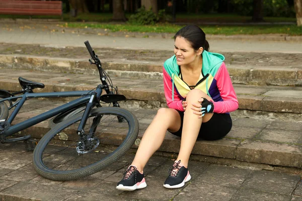 若いです女性負傷膝上のステップ近く自転車屋外 — ストック写真