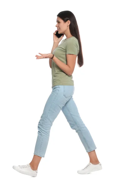 Νεαρή Γυναίκα Μιλάει Στο Τηλέφωνο Ενώ Περπατάει Λευκό Φόντο — Φωτογραφία Αρχείου