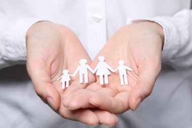 Woman holding paper family figures, closeup. Insurance concept clipart