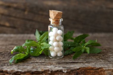 Bir şişe homeopatik ilaç ve tahta masada nane şekeri.