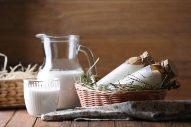 Sürahide taze süt, şişeler ve bardaklar ahşap masada