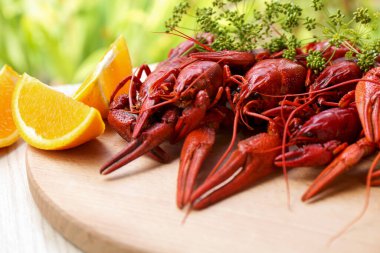 Lezzetli kırmızı kaynatılmış kerevit ve portakal tahtada, yakın plan.