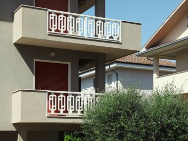 Güneşli bir günde balkonlu bir apartmanın dışı.