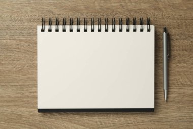 Defter ve kalem ahşap masada, düz yatıyordu.