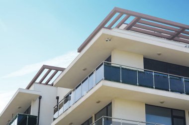Mavi gökyüzüne karşı balkonu olan binanın dışı, alçak açılı görünüm