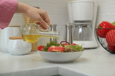 Mutfakta salatayla sürahide yağ döken kadın, yakın plan.