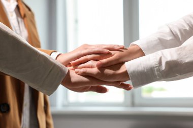 Group of people holding hands together indoors, closeup. Unity concept