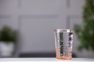 Glass of clean water on white table indoors, space for text