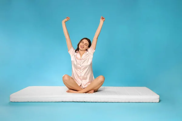 Mujer Joven Estirándose Sobre Colchón Suave Sobre Fondo Azul Claro —  Fotos de Stock