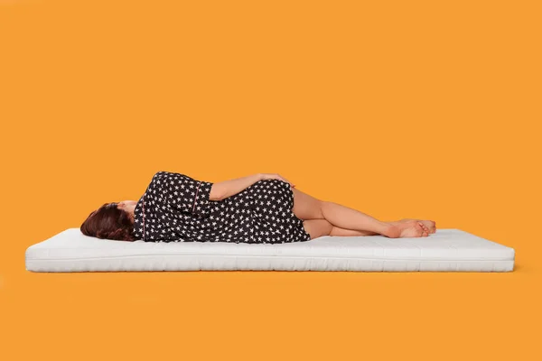 Mujer Joven Durmiendo Colchón Suave Sobre Fondo Naranja Vista Trasera —  Fotos de Stock