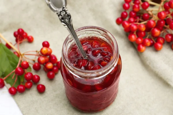 stock image Jar with spoon and tasty viburnum jam on table