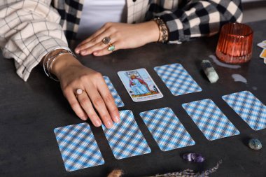 Falcı, gri masada tarot kartlarının yayılması üzerine geleceği tahmin ediyor, yakın plan.