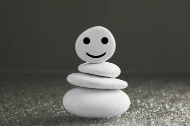 Gri arka planda mutlu yüzü çizilmiş taşlar yığını. Zen kavramı