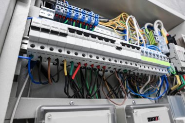 Elektrik sayaçları ve sigorta kutusunda bir sürü kablo olan panel