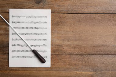 Orkestra şefinin copu ve notaları ahşap masanın üstünde, üst tarafta. Metin için boşluk